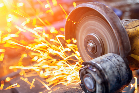 Close up of a  welder grinds a metal object with a angle  grinder in the garage, bright sparks fly to the sidesの写真素材