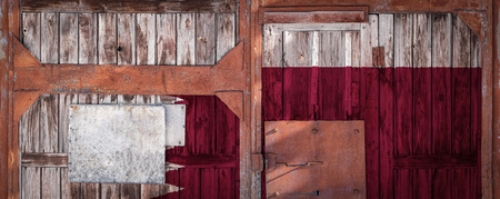 Close-up of old warehouse gate with national flag of Qatar. The concept of export-import Qatar, storage of goods and national delivery of goods. Flag in grunge styleの写真素材