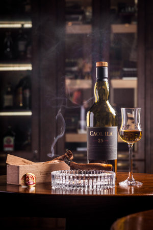 Novosibirsk, Russia - April 07, 2017:  Caol ila Single Malt Whisky,lit cigar and a glass of whiskey   at the bar wooden counterのeditorial素材