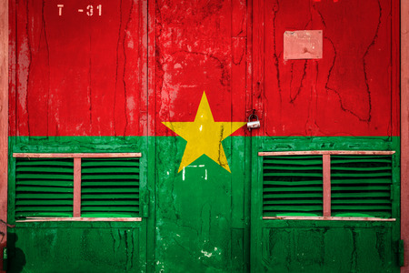 Close-up of old warehouse gate with national flag of Burkina Faso. Concept of  Burkina Faso export-import, storage of goods and national delivery of goods. Flag in grunge styleの写真素材
