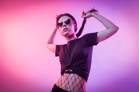 High Fashion model  woman in fashion t-shirts and pants with stripes in colors lgbt in colorful bright neon uv blue and pink lights, posing in studio. Fashion concept and Zine cultureの写真素材