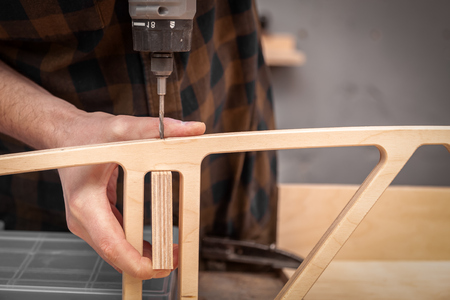 Profesional drilling wood on vertical drill machine. Close up of a metal drill making holes in the wood.の写真素材