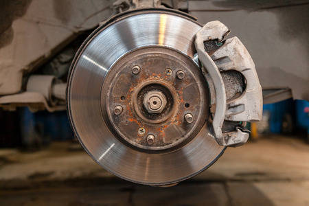 Close-up of heavily worn rear drum brakes on a car raised on a lift in a car repair shopの写真素材