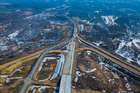 Aerial drone top view photo of track road in the industrial area with construction sites in the springtime with unmelted iceの写真素材