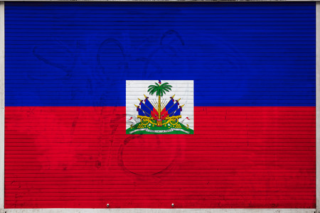 Close-up of old metal wall with national flag of Haiti. Concept of Haiti export-import, storage of goods and national delivery of goods. Flag in grunge styleの写真素材