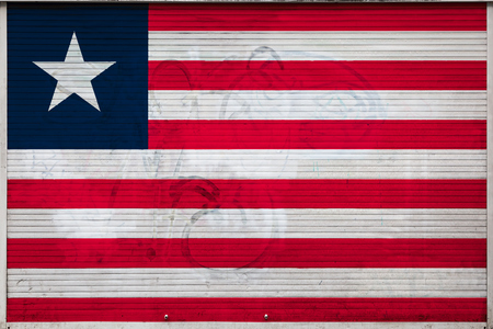 Close-up of old metal wall with national flag of Liberia. Concept of Liberia export-import, storage of goods and national delivery of goods. Flag in grunge styleの写真素材
