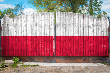 Close-up of the national flag of Poland on a wooden gate at the entrance to the closed territory on a summer day. The concept of storage of goods, entry to a closed area, tourism in Polandの写真素材
