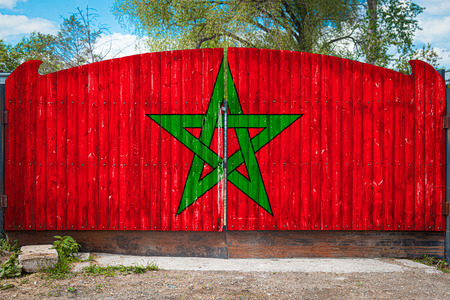 Close-up of the national flag of Morocco on a wooden gate at the entrance to the closed territory on a summer day. The concept of storage of goods, entry to a closed area, tourism in Moroccoの写真素材
