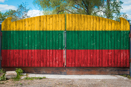 Close-up of the national flag of Lithuania on a wooden gate at the entrance to the closed territory on a summer day. The concept of storage of goods, entry to a closed area, tourism in Lithuaniaの写真素材