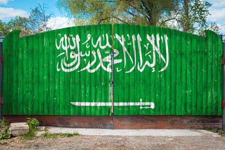 Close-up of the national flag of Saudi Arabia on a wooden gate at the entrance to the closed territory on a summer day. The concept of storage of goods, entry to a closed area, tourism in Saudi Arabiaの写真素材