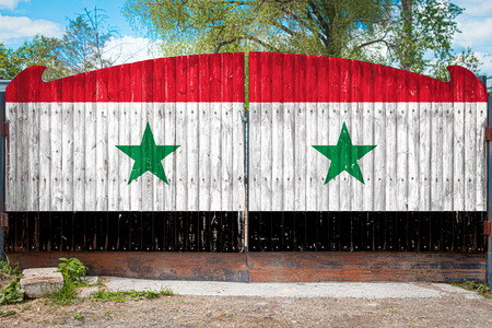 Close-up of the national flag of Syria on a wooden gate at the entrance to the closed territory on a summer day. The concept of storage of goods, entry to a closed area, tourism in Syriaの写真素材