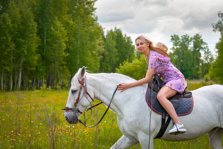 Young woman  in romantic dress with her  white horse in evening sunset light. Outdoor photography with fashion model girl. Lifestyle moodの写真素材