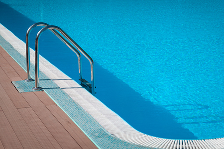 Handrail on pool. Swimming pool with stair at tropical resort. Water swimming pool with sunny reflection. Steel handrail, swimming, summer, travel. Entry to pool with handrail.の写真素材