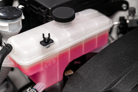 Close-up white expansion tank with pink antifreeze. Car coolant level in radiator system in car,...