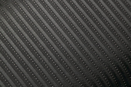 Close-up black car seat trim. Soft rough carbon fabric texture.