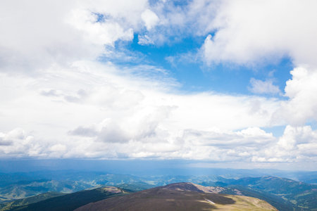 Ultra wide panorama of skyline. Green mountains covered with forest on the blue sky background. ...