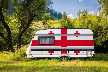 A car trailer, a motor home, painted in the national flag of Georgia stands parked in a mountainous. The concept of road transport, trade, export and import between countries. Travel by carの写真素材