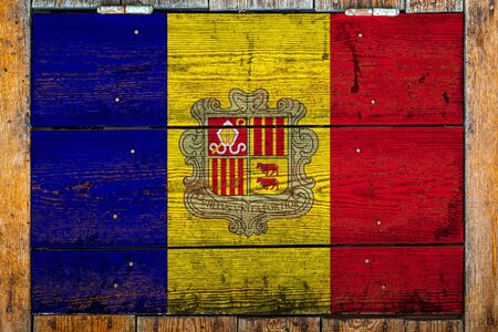 National flag of Andorra on a wooden wall background.The concept of national pride and symbol of the country.Flag painted on a wooden fence with metal nails.の写真素材