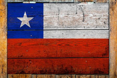 National flag of Chile on a wooden wall background.The concept of national pride and symbol of the country.Flag painted on a wooden fence with metal nails.の写真素材