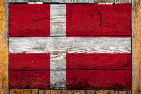 National flag of Denmark on a wooden wall background.The concept of national pride and symbol of the country.Flag painted on a wooden fence with metal nails.の写真素材