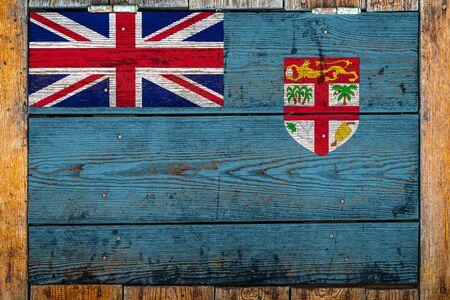 National flag of Fiji on a wooden wall background.The concept of national pride and symbol of the country.Flag painted on a wooden fence with metal nails.の写真素材