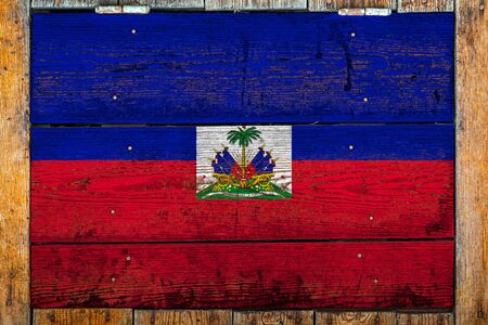 National flag of Haiti on a wooden wall background.The concept of national pride and symbol of the country.Flag painted on a wooden fence with metal nails.の写真素材