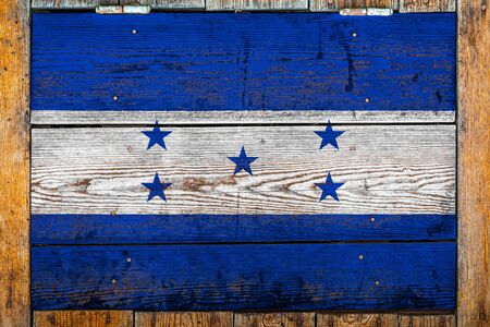 National flag of Honduras on a wooden wall background.The concept of national pride and symbol of the country.Flag painted on a wooden fence with metal nails.の写真素材