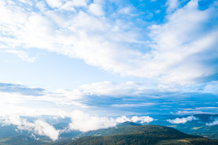 Ultra wide panorama of skyline. Green mountains covered with forest on the blue sky background. ...