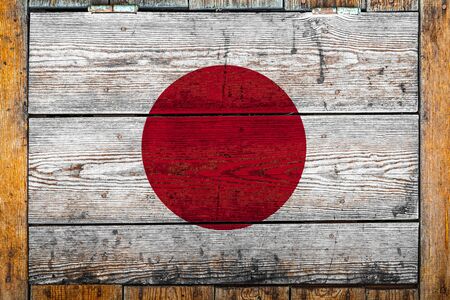National flag of Japan on a wooden wall background.The concept of national pride and symbol of the country.Flag painted on a wooden fence with metal nails.の写真素材