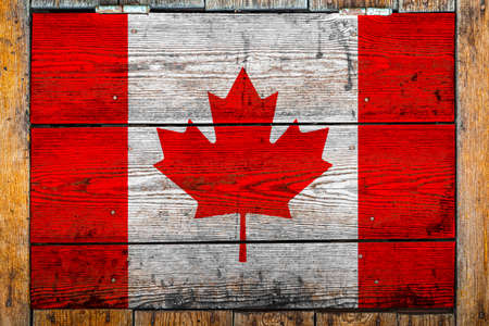 National flag of Canada on a wooden wall background.The concept of national pride and symbol of the country.Flag painted on a wooden fence with metal nails.の写真素材