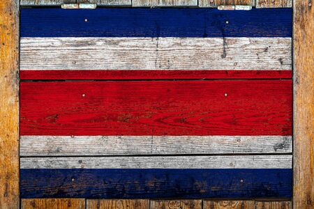 National flag of Costa Rica on a wooden wall background.The concept of national pride and symbol of the country.Flag painted on a wooden fence with metal nails.の写真素材