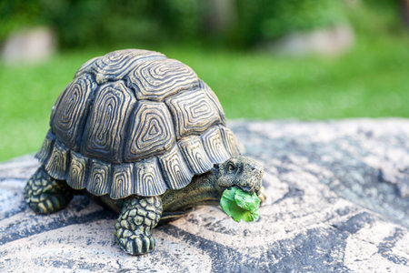 Close-up of a large turtle in a stone shell - decorations for the garden on a garden stone on a...