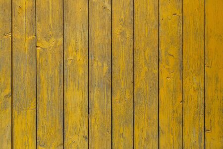 Close-up of a   yellow wooden  wall  painted a very long time and the paint peeled off.  Yellow texture backgroundの写真素材