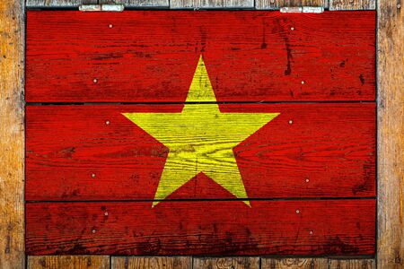 National flag of Vietnam on a wooden wall background.The concept of national pride and symbol of the country.Flag painted on a wooden fence with metal nails.の写真素材