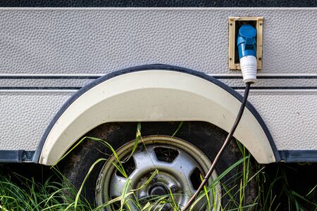 Close-up of a gas tank  with an inserted gun for supplying fuel to an old car on the street, against a background of green grass. Exterior of car with fuel filler door open.の写真素材