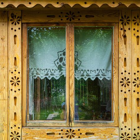 Russian architecture. Close-up old beautiful window with wooden shutters artificially carved from pine tree on a wooden houseの写真素材