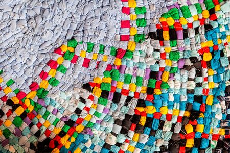 A close-up of an old floor mat woven in a special way from rags of clothing fabric. Woven fabric textureの写真素材