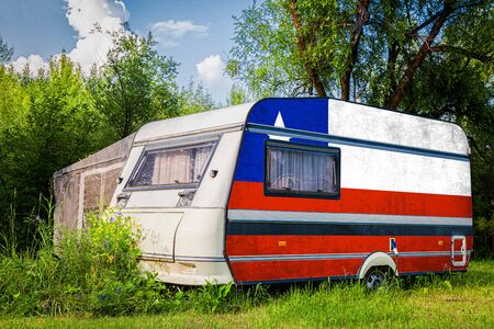 A car trailer, a motor home, painted in the national flag of  Chile stands parked in a mountainous. The concept of road transport, trade, export and import between countries.の写真素材