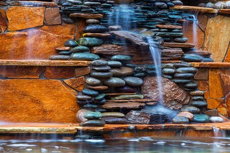 Larger plan A beautiful fountain, made of different stones, water flows from several clay jugs into a large pool with clear water. Pacifying picture of running waterの写真素材