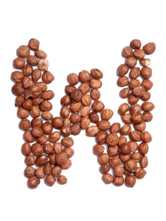 Letter W of the English alphabet from from hazelnut on a white isolated background. Food pattern made from nuts. Bright alphabet for shops. の写真素材