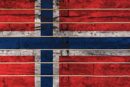 National flag  of Norway on a wooden wall background. The concept of national pride and a symbol of the country. Flags painted on a wooden fence with a ropeの写真素材