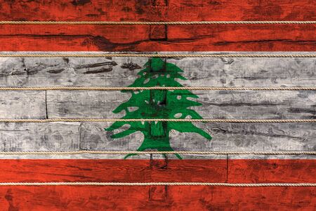 National flag  of Lebanon on a wooden wall background. The concept of national pride and a symbol of the country. Flags painted on a wooden fence with a ropeの写真素材
