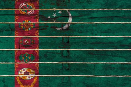 National flag  of Turkmenistan on a wooden wall background. The concept of national pride and a symbol of the country. Flags painted on a wooden fence with a ropeの写真素材