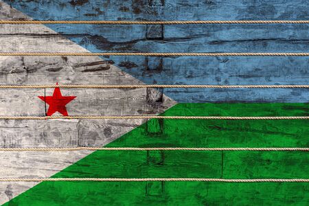 National flag  of Djibouti
 on a wooden wall background. The concept of national pride and a symbol of the country. Flags painted on a wooden fence with a ropeの写真素材