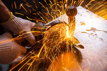Close-up of a man sawing   bearing metal brake disk with a hand circular saw, bright flashes flying...