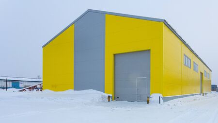 Facade of a yellow metal warehouse, a commercial building with entrances for cars for storing goods. The concept of storage of goods by importers, exporters, wholesalers, transport enterprises, customの写真素材