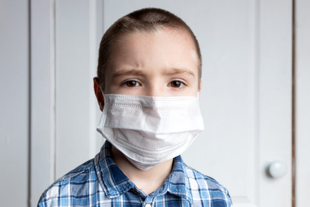 Young boy with sore eyes in a medical mask look at camera. Medical protection against airborne diseases, coronavirus. Ð¡hild is afraid of getting the fluの写真素材