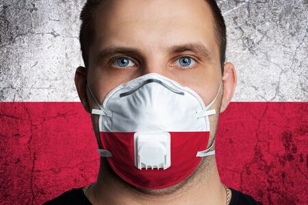 Young man with sore eyes in a medical mask painted in the colors of the national flag of Poland. Coronovirus disease  COVID-19 concept.  Man is afraid of getting the fluの写真素材
