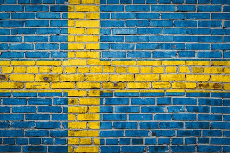 National flag of Sweden  depicting in paint colors on an old brick wall. Flag  banner on brick wall background.の写真素材