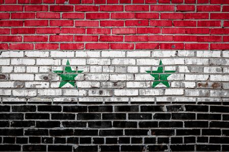 National flag of Syria depicting in paint colors on an old brick wall. Flag  banner on brick wall background.の写真素材